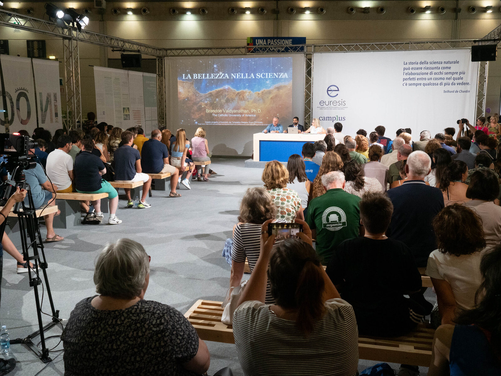 A large audience attending a presentation about beauty in science