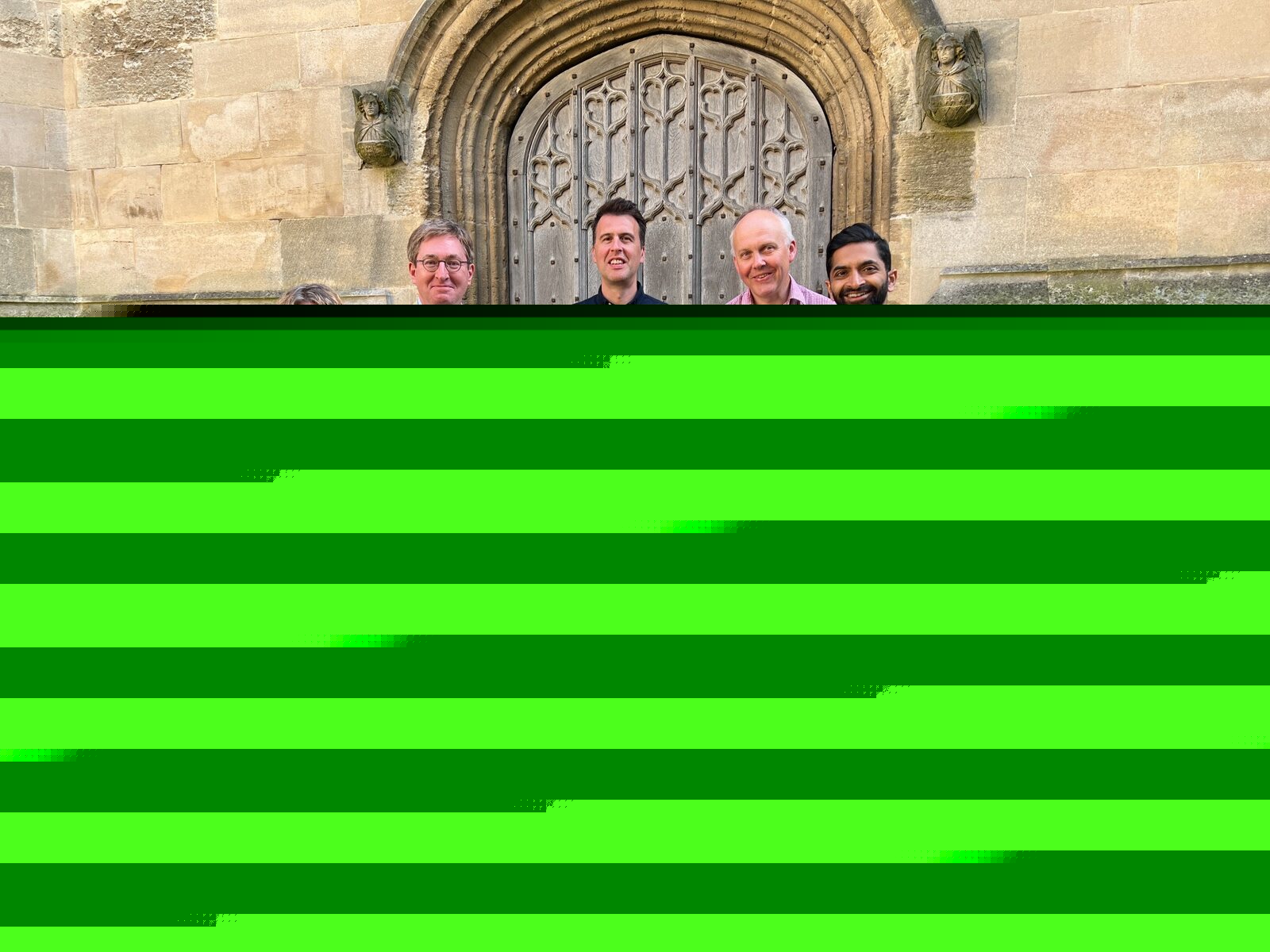 Five project participants gathered outside a historic stone building