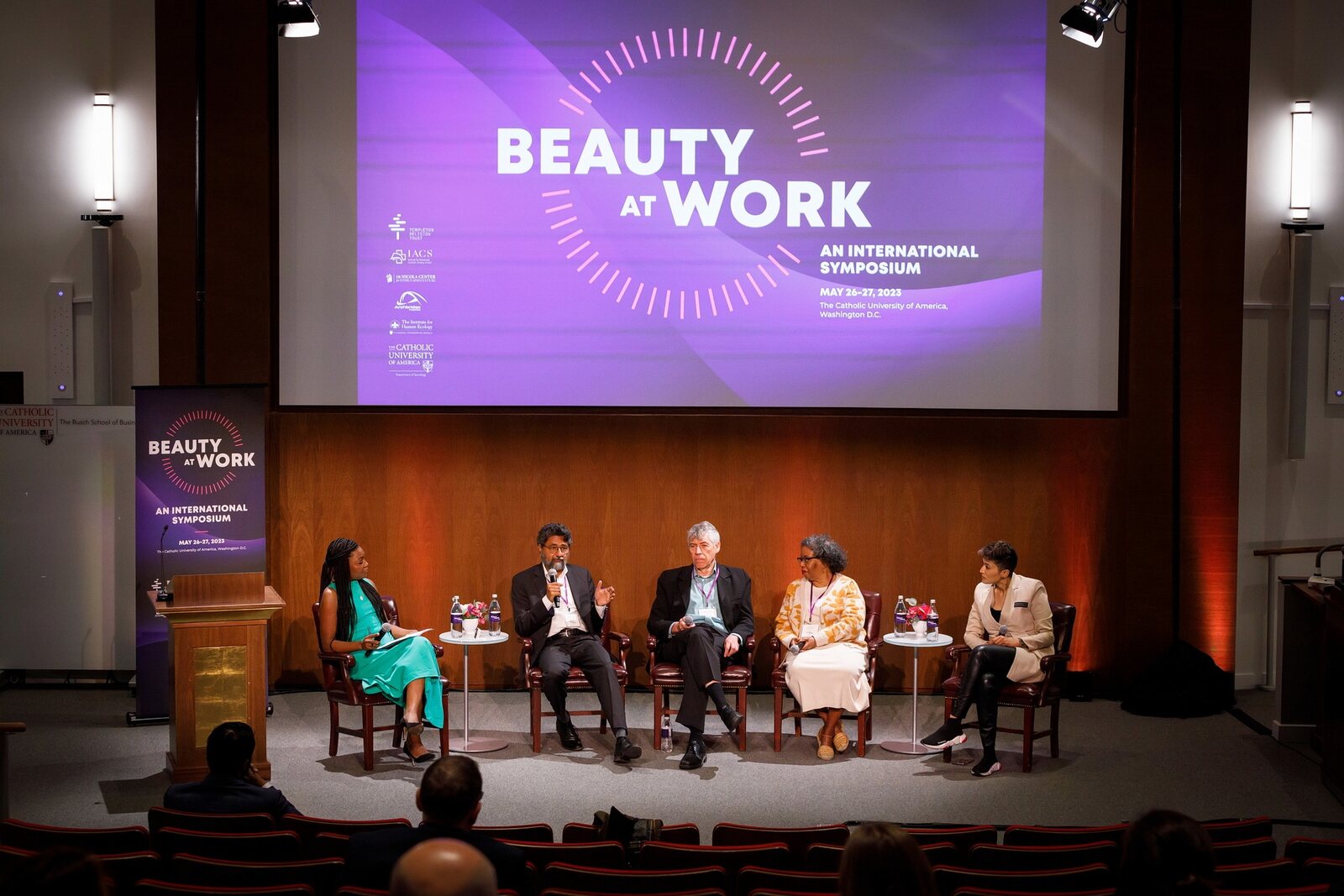 Panelists speaking onstage at the Beauty at Work international symposium